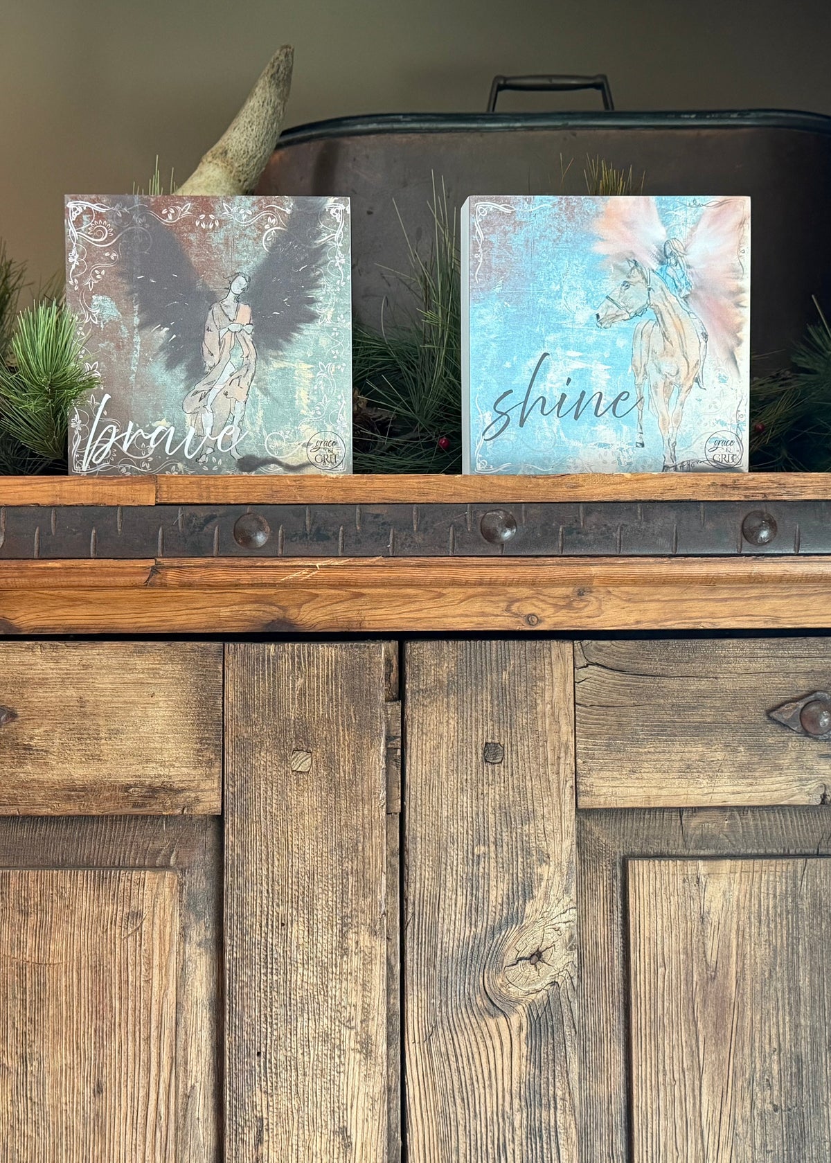 Decorative signs with angel designs and motivational phrases on a wooden surface.