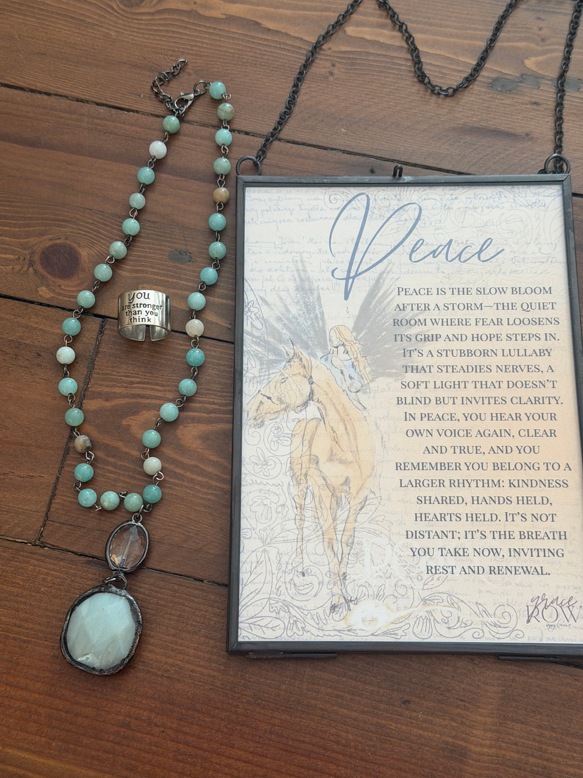Necklace with turquoise beads and silver clasp on a wooden surface with a framed text and illustration.