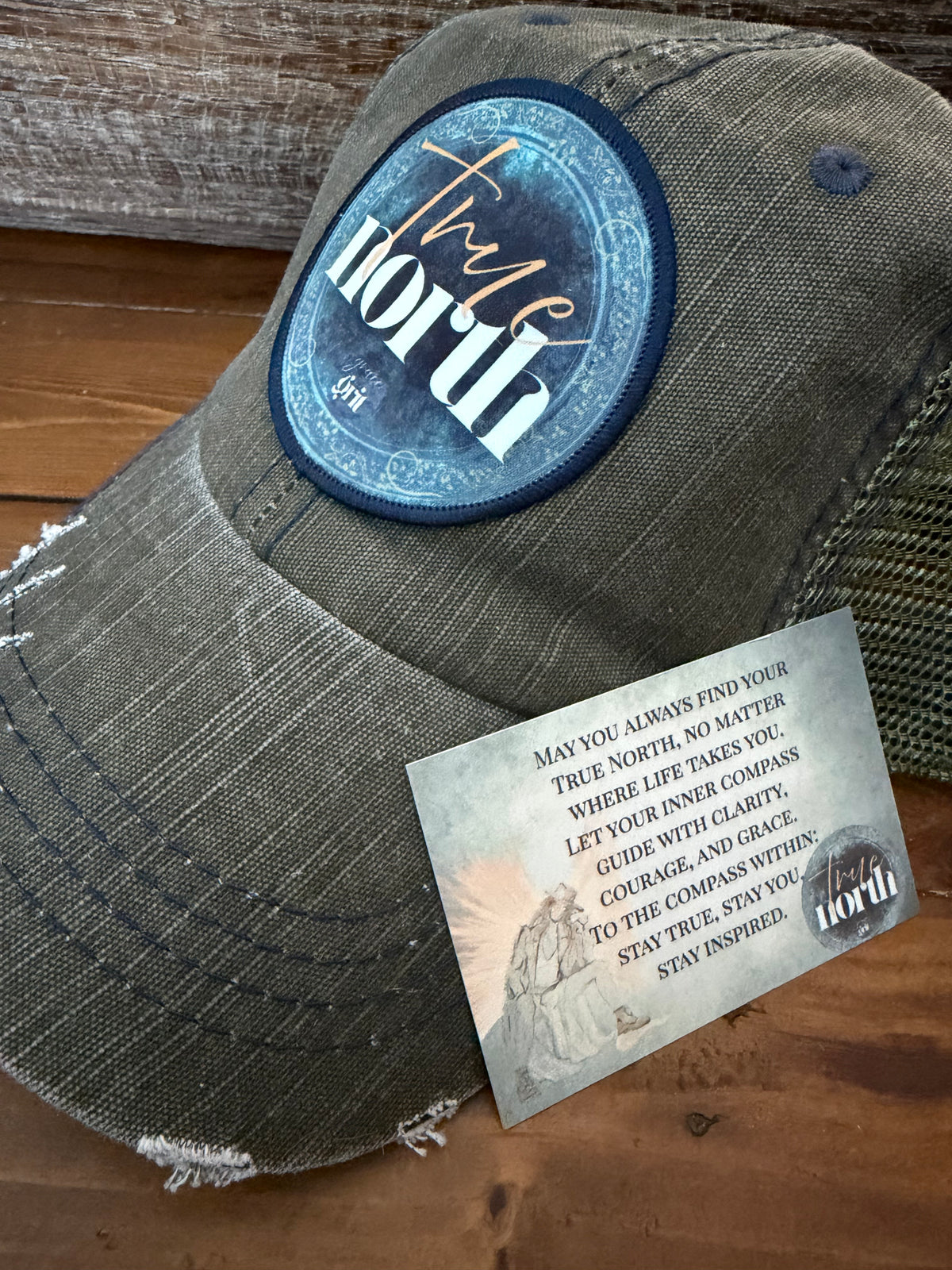 Gray cap with 'True North' patch and tag on a wooden surface