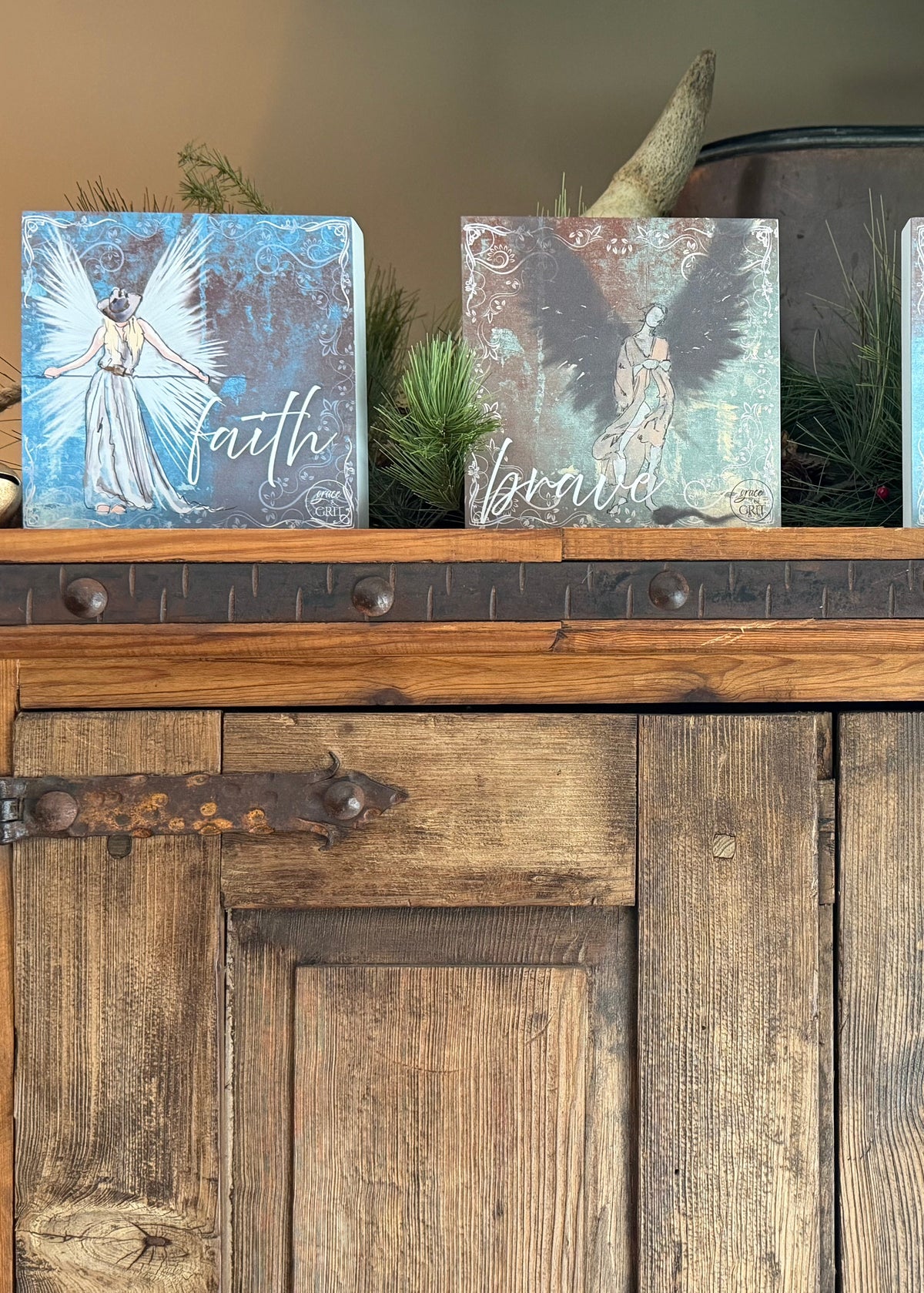 Decorative signs with angel designs and motivational phrases on a wooden surface.