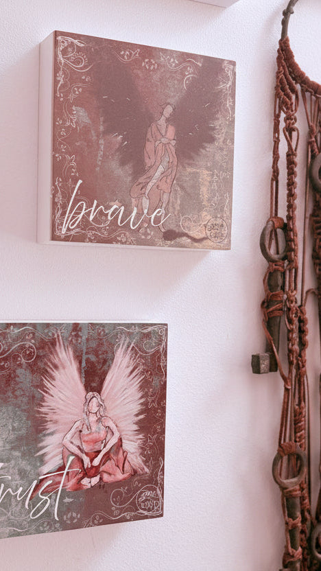 Decorative wall art with angel illustrations and a dreamcatcher on a white wall.