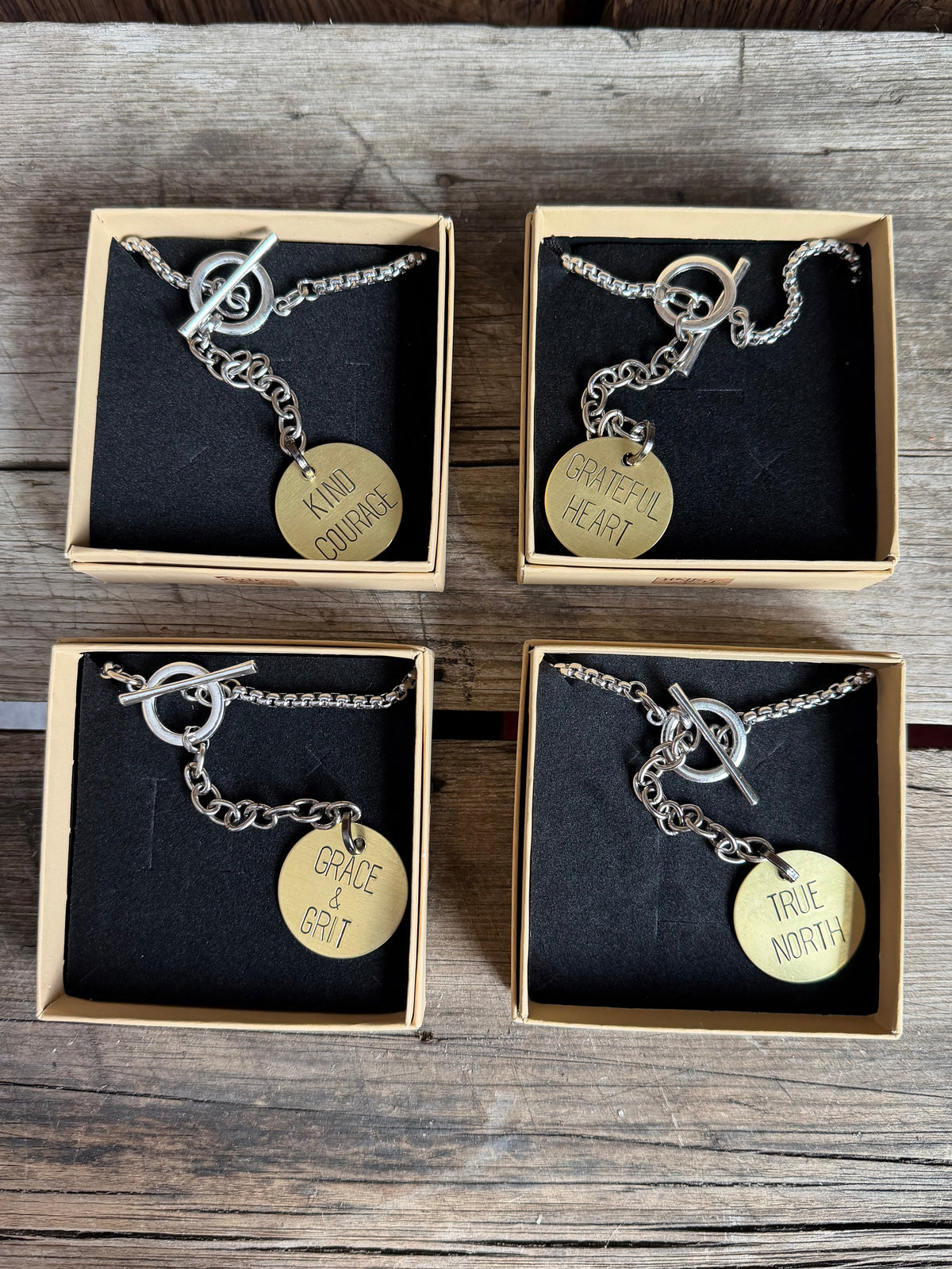 Four jewelry boxes with necklaces and pendants on a wooden surface